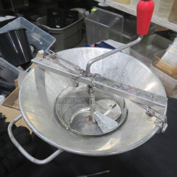 Manual One Meal Grinder with stainless steel bowl, red handle, and crank. Features mesh strainer. Used condition.