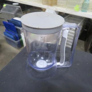 Transparent batter dispenser with white handle and gray lid, marked with ml measurements. Shows minor wear, ideal for precise batter dispensing.