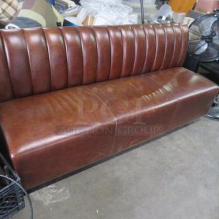 Brown cushioned booth, single-sided, 75x27x34 inches. Features vertical stitching, good condition, ideal for dining spaces.