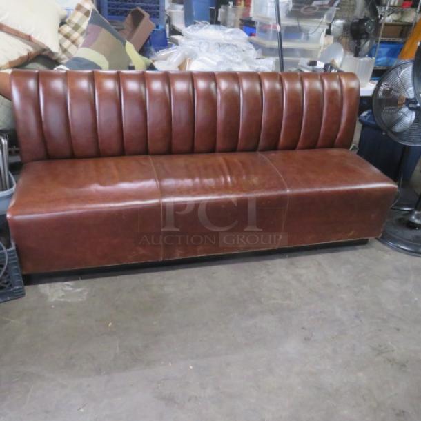Brown cushioned single-sided booth bench, 75x27x34 inches, ribbed backrest, good condition, ideal for dining spaces.