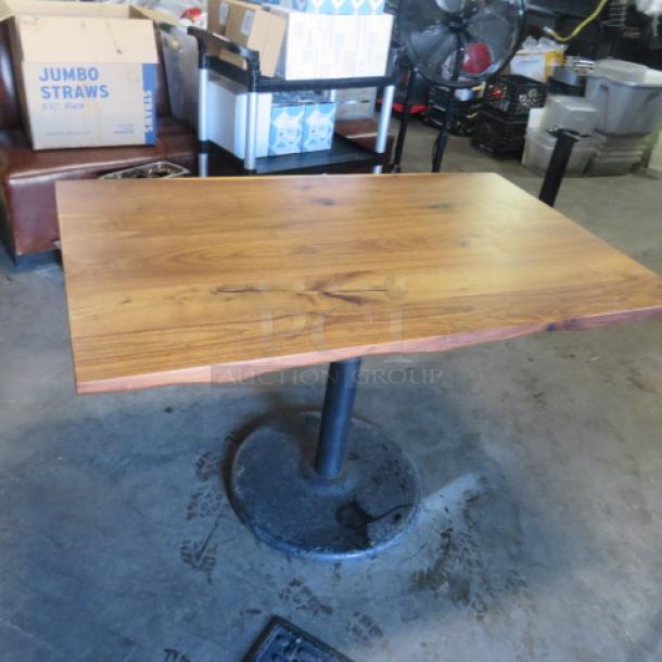Solid wooden table on a pedestal base, 48x30x30 inches, natural finish, gently used, subtle wood grain details.