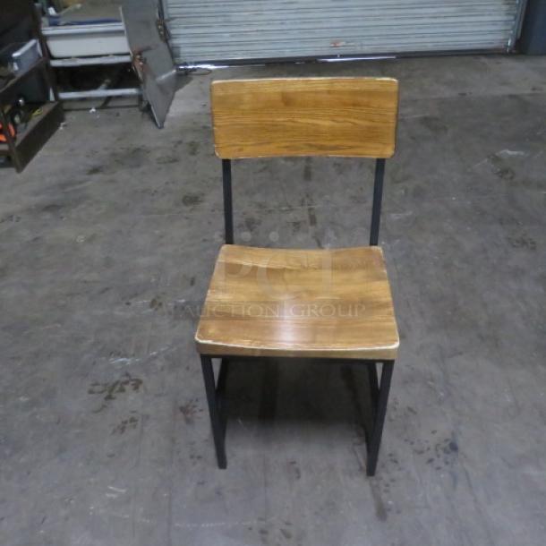 Industrial black metal chair with wooden seat and back. Good condition, sturdy design. Ideal for modern interiors.