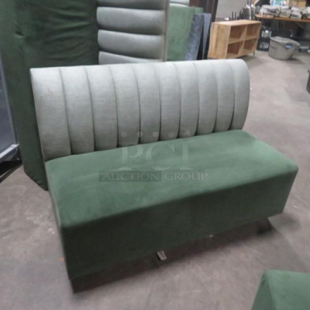 Single-sided green cushioned booth, 50"x26"x34". Features include a ribbed backrest and plush seat, in good condition.