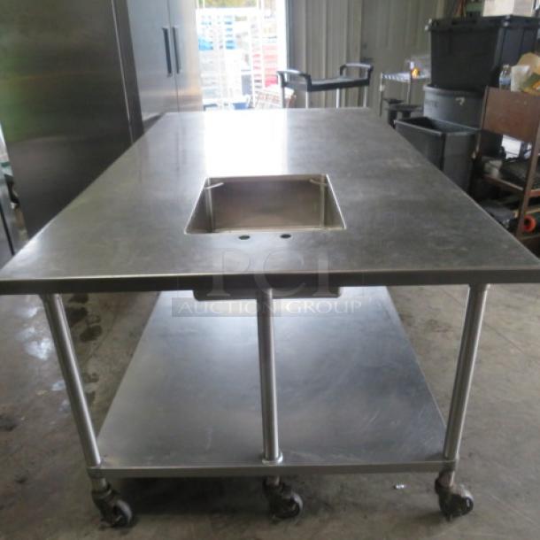 Stainless steel table with 20x16 sink, SS under shelf, on casters. Dimensions: 84x48x35 inches.