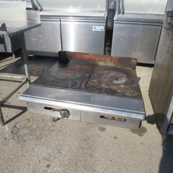 Natural gas 2-burner tabletop range, 36x43x16 inches. Features a stainless steel finish and visible signs of use. Adjust knobs below burners.