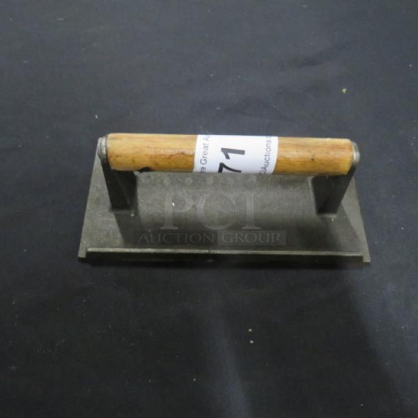 Heavy-duty metal weight with a robust wooden handle, labeled "771." Used for pressing or flattening tasks.