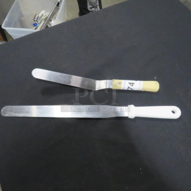 Two assorted spreaders with stainless steel blades; one with a yellow handle labeled "74," the other with a white handle.