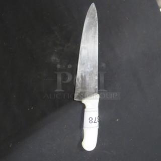 Chef's knife with white handle, visibly used. Blade shows wear. Marked with number 878 for identification.