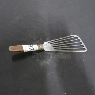 Metal fish turner with slotted blade and wooden handle, item number 92, in used condition.