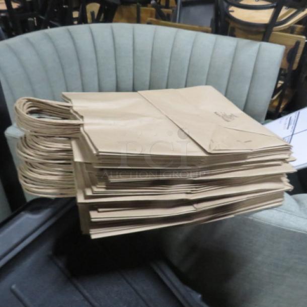 Stack of brown paper to-go bags with handles in good condition.