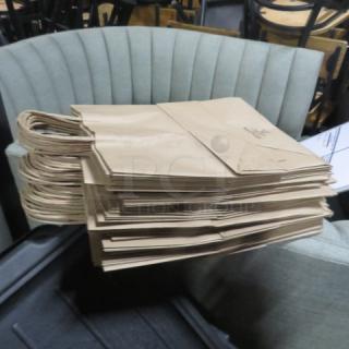 Stack of brown paper to-go bags with handles in good condition.