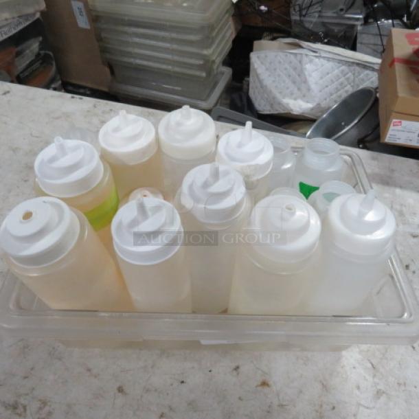 One lot of assorted clear squeeze bottles with white caps in used condition, displayed in a clear tray.
