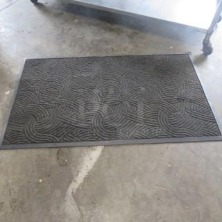 Dark gray rug, 59x39 inches, with interlocking swirl pattern. Slight wear visible. No tags or labels present.