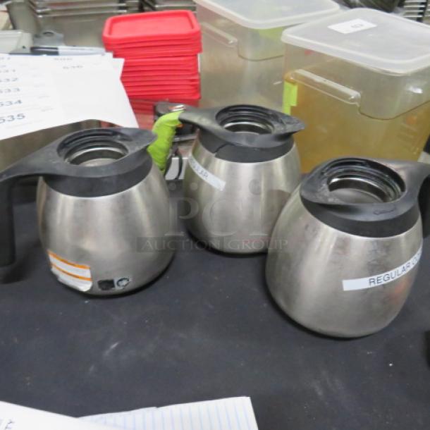 Stainless steel coffee pot with black handle and lid. Visible labels indicate contents. Used condition.