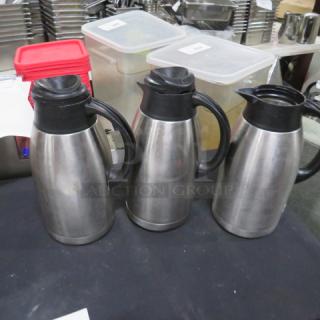 Three Bunn stainless steel creamers with black plastic lids and handles, in good condition, displayed on a table.