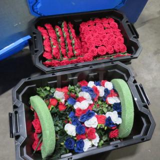 Large assortment of faux flowers in red, white, and blue, stored in black bins. TOTE NOT INCLUDED.