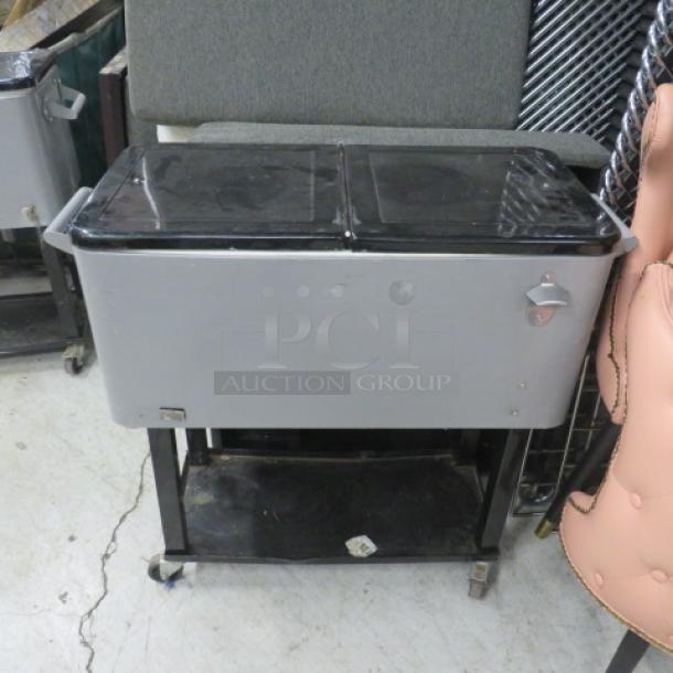 Portable beverage/ice cooler with flip lid, undershelf, bottle opener, on casters. Dimensions: 35.5x16x34 inches.