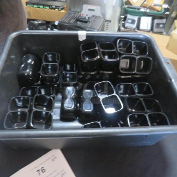 One lot of 32 black melamine dual condiment servers in a gray bussing tub, excellent condition.