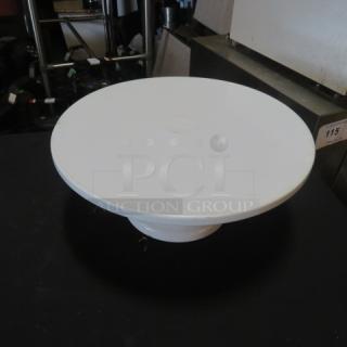 Round white cake stand, 12x6 inches, on a single pedestal. Smooth surface, minimalist design, suitable for cakes or desserts.