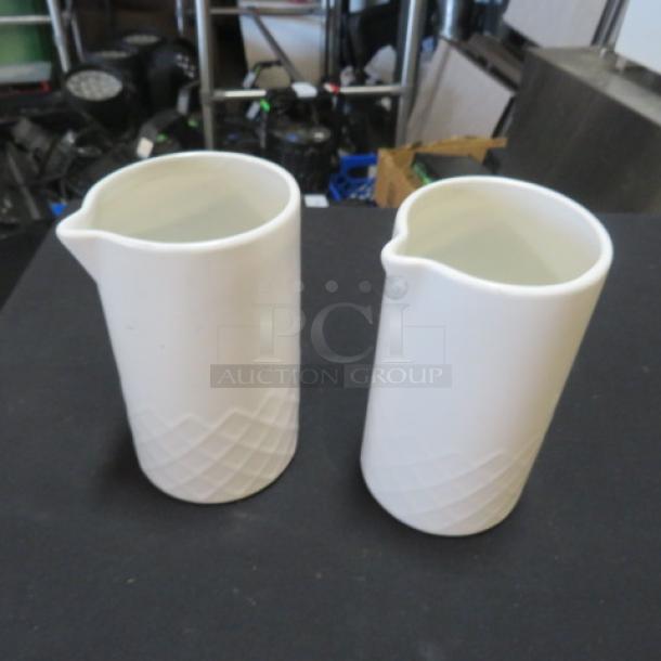 Pair of white ceramic creamers with geometric embossed pattern; clean, mint condition.