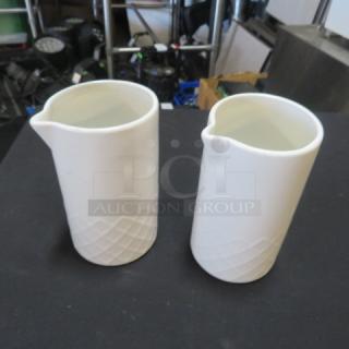 Pair of white ceramic creamers with geometric embossed pattern; clean, mint condition.