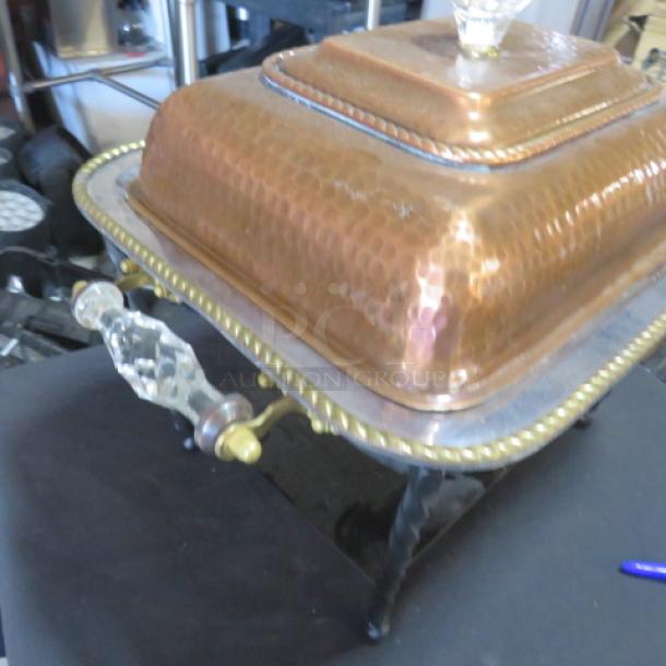 Hammered copper half-size chafer with glass knob and handles. Features intricate detailing, indicating quality craftsmanship.