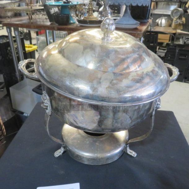 Round silver plate chafing dish with lion's head handles and lid; vintage condition, ornate detailing on base.