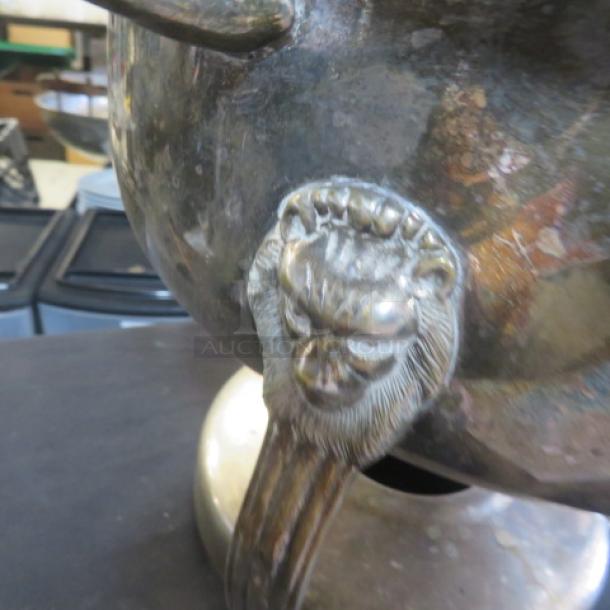 Silver plate chafer with lid, featuring a lion's head detail. Some tarnish visible, round shape, elegant design.