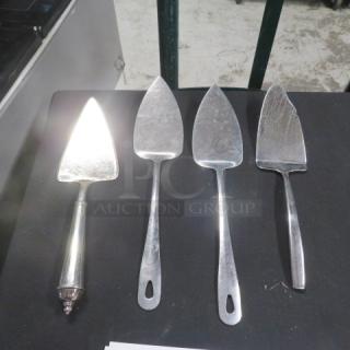 Four assorted pie servers on display; metal, varying handle designs, moderate wear visible, suitable for serving pies.