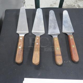 Assorted pie servers with wooden handles and stainless steel blades, set of four. Used condition, visible wear on handles.