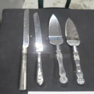 Assorted serving utensils, including two knives and two pie servers, with ornate handles, showing minor wear.