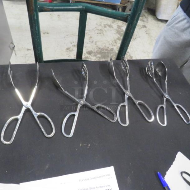 Four stainless steel buffet tongs on display. Good condition with ergonomic handles, suitable for catering or serving.