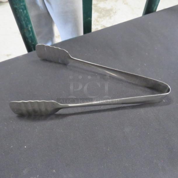 Stainless steel 9-inch pastry tong, new condition. Features serrated edges for grip. Ideal for serving pastries.