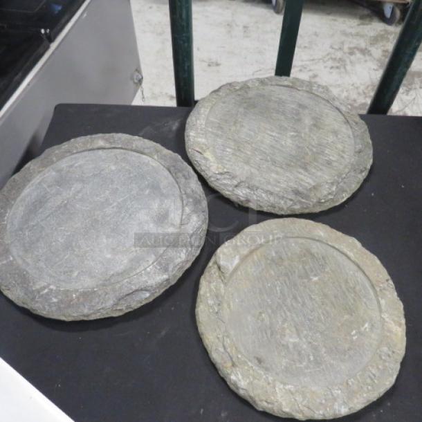 Three heavy decorative buffet catering plates, stone material, rustic appearance, good condition, on display surface.
