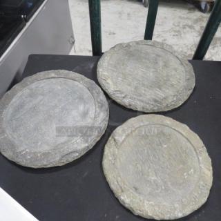 Three heavy decorative buffet catering plates, stone material, rustic appearance, good condition, on display surface.