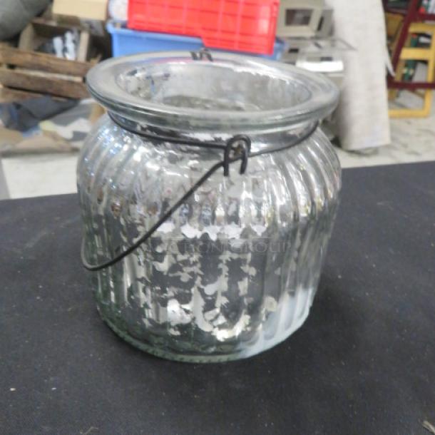 Silver candle holder with ribbed glass design. Features a metal handle. Good condition. Model 8XBID.