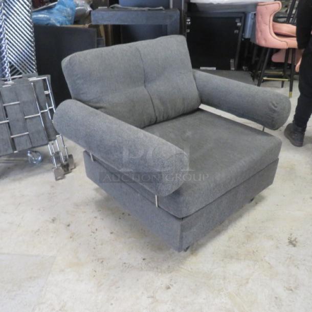 Comfortable gray chair with plush upholstery, cylindrical armrests, and metal accents. Dimensions: 43x33x32 inches. Good condition.