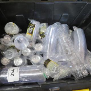 New disposable shot glasses in clear plastic packaging, various stacks in a bin. Each pack labeled with brand details.