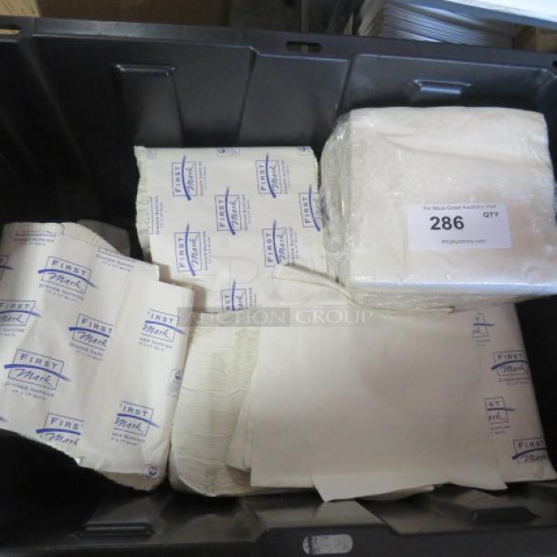 One lot of dinner napkins in plastic bins, featuring "First Mark" branding on packaging. Includes wrapped stack with auction label "286".