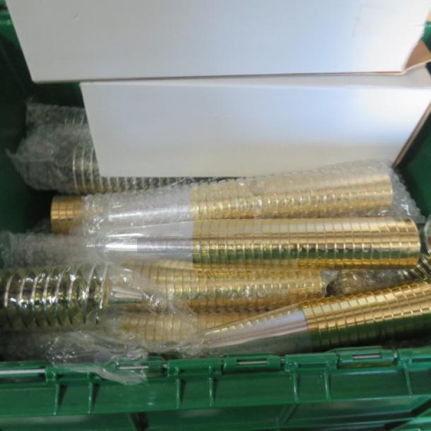 A lot of gold-toned disposable champagne glasses, stacked and wrapped in bubble wrap, in a green bin.