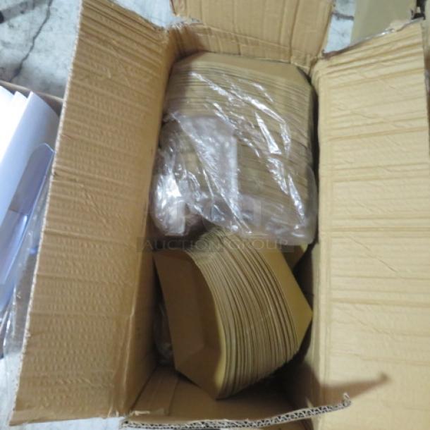 Open cardboard box containing a lot of brown paper boats, neatly stacked and partially wrapped in plastic.