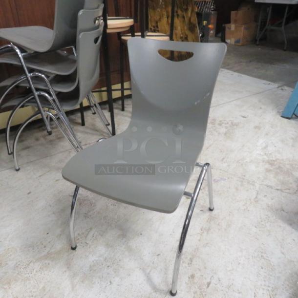Metal wooden stack chair, gray seat, chrome legs, modern design, used condition, model 2XBID, stackable for easy storage.