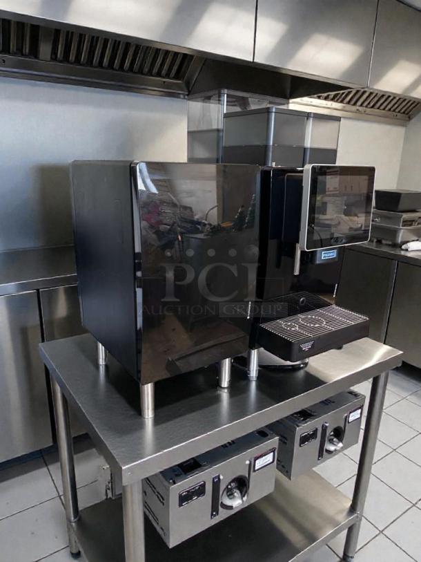 Brand new Franke A1000 FCS4050 commercial coffee machine on metal table. Black exterior, touchscreen, UL/NSF listed.