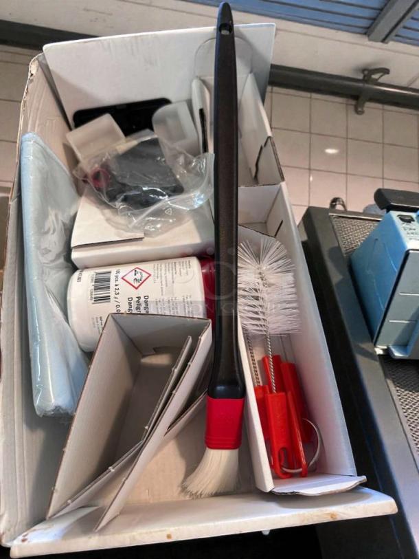 Box containing cleaning brushes, a cleaning solution, and accessories for the Franke A1000 commercial coffee machine.