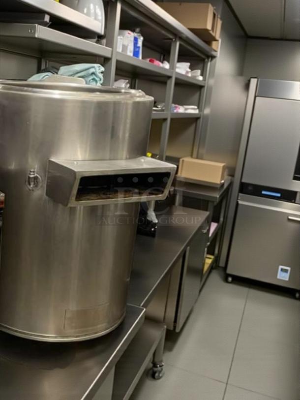 Stainless steel commercial steam-jacketed kettle with agitator in premium condition on a kitchen counter.