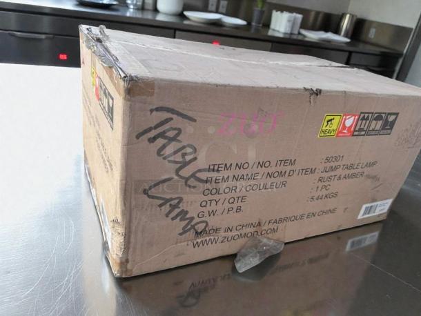 Brand new Zuomor Jump Table Lamp set in box, 3-light, rustic amber glass, decorative, model 50301, original packaging.