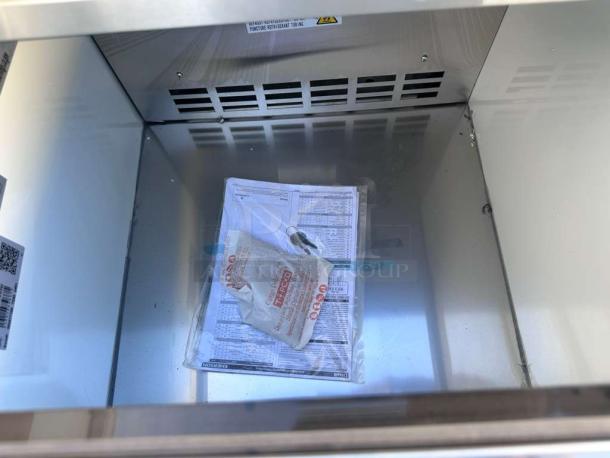 Brand new KoolMore KM-BC25-BK black commercial bottle cooler interior, showing documentation and label, UL & NSF listed.