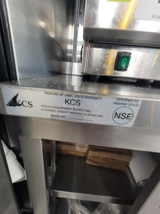 Commercial stainless steel work table with sliding doors, model KCS 415, label shows NSF certification, by KCS Equipment Supply Inc.