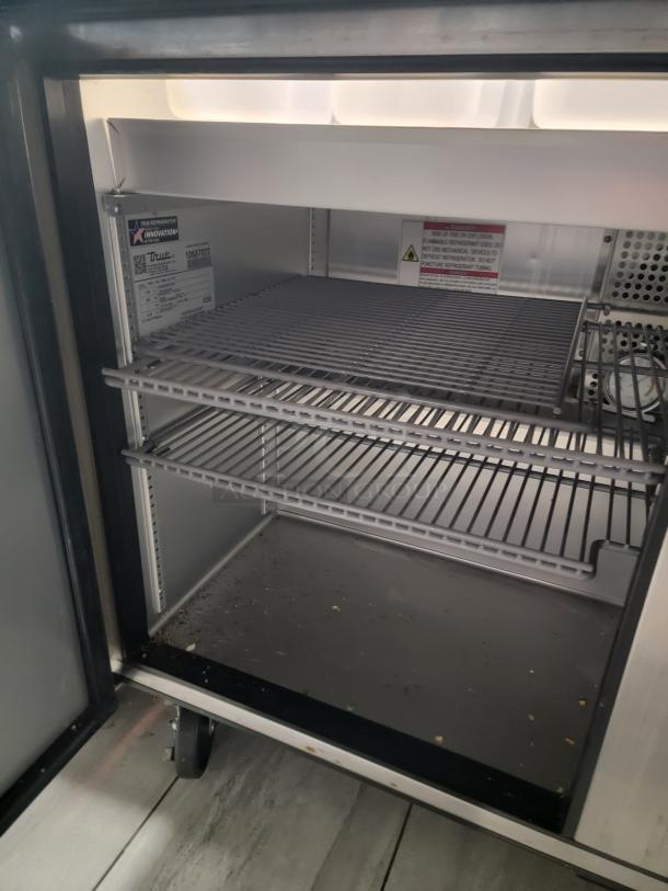 True TSSU-48-18M-B-HC prep table interior, showing spacious shelves, model tag, and eco-friendly refrigerant label.