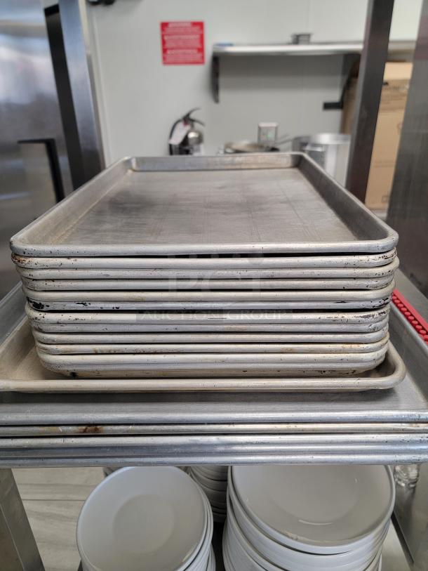 Stainless steel shelving unit with stacked sheet pans and multiple ceramic plates. Ideal for commercial-grade kitchen storage.